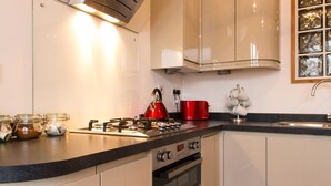 Cucina con piano cottura a gas, bollitore rosso e tostapane. Sul bancone ci sono dei barattoli e un lavello con rubinetto.
