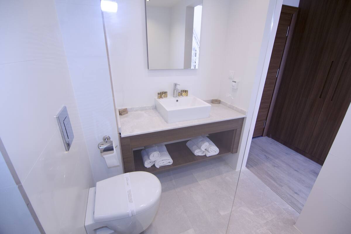 A modern bathroom with a white sink, mirror, and toilet.