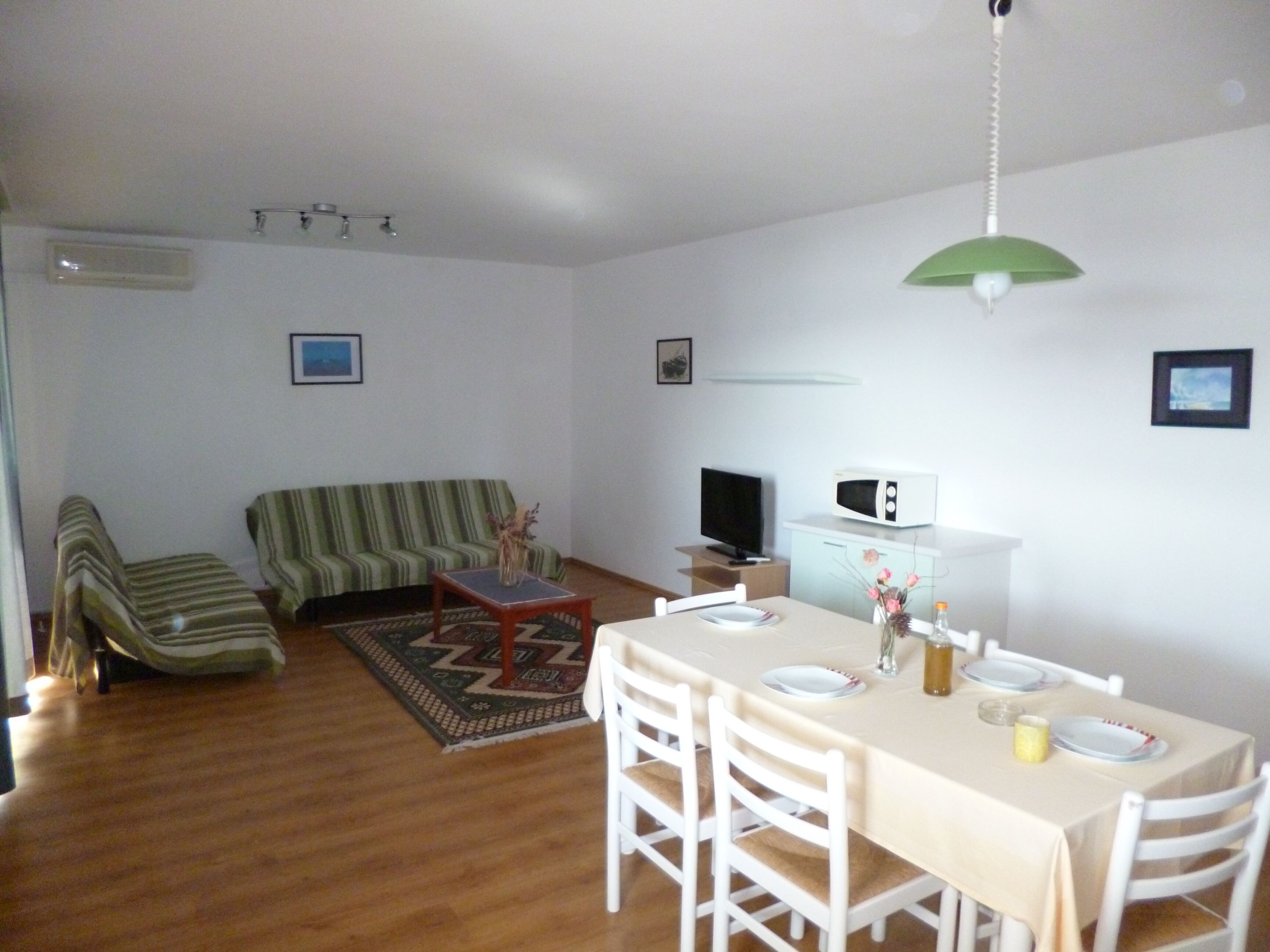 Un salon comprenant un canapé, une table à manger avec des chaises, un téléviseur et un four à micro-ondes.