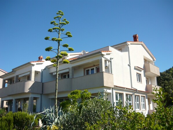A two-story building with a balcony on the second floor, a satellite dish on the roof, and a clear blue sky. - Blue apartment Jadro island Rab (Barbat)