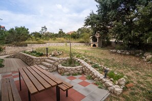 A stone-walled garden with a wooden bench and a stone fireplace. - Blue apartment Jadro island Rab (Barbat)