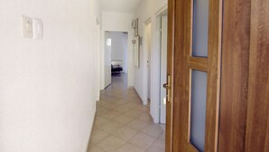 Ein Flur mit einer Holztür, weißen Wänden und einem gefliesten Boden.