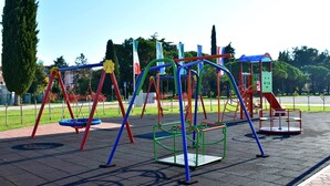 Ein Spielplatz mit Schaukeln, Klettergerüsten und einer Rutsche.