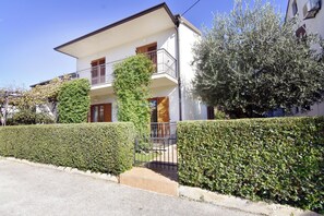 A two-story residential building with a balcony and a gated entrance. - Two-bedroom apartment, downtown Umag, near the beach, Wi-Fi (Umag)