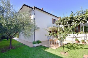 A white house with a patio area, outdoor seating, and a garden. - Two-bedroom apartment, downtown Umag, near the beach, Wi-Fi (Umag)