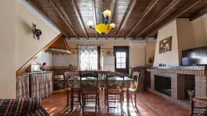 Una sala de estar acogedora con chimenea, un comedor con mesa de vidrio y una cocina equipada con microondas y tostadora.