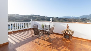 Una terraza con una mesa, sillas, una planta en maceta y una pequeña chimenea.