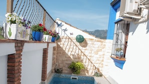 Una piscina con borde de azulejos, baranda de metal y plantas en macetas.