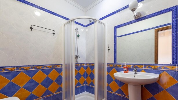 A bathroom with a shower, toilet, and sink, featuring blue and orange patterned tiles. - TEON HOUSE WITH PRIVATE POOL (Montecorto)