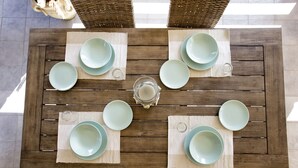 Une table de salle à manger en bois, accompagnée de quatre chaises, mise avec des assiettes, des verres et une bougie.