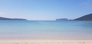 A beach with clear water and distant hills. - Alghero superior villa close to the beaches (Santa Maria La Palma)