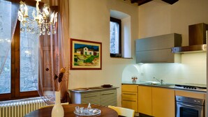 A dining table with a vase and glassware, a kitchen with modern appliances, and a painting on the wall.