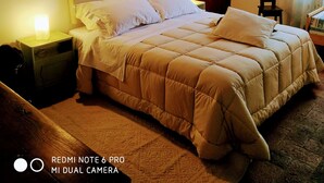 A bedroom with a bed, bedside tables, a lamp, and two framed pictures on the wall.