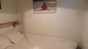 Una cama con una colcha blanca y una fotografía enmarcada de una persona sobre la cabecera.