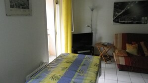 Una habitación con una cama, televisión, sofá y un cuadro en la pared.