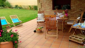 Eine Terrasse mit Esstisch, umgeben von Holzstühlen und einer Bank.