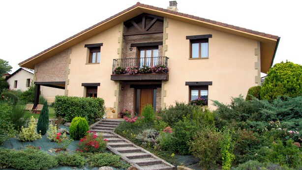 Ein zweistöckiges Haus mit Balkon, einer Haustür und einer Treppe zum Eingang.