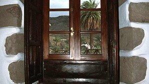 Una puerta de madera con un ventanal, en una pared de piedra.