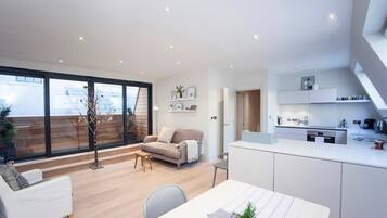 A modern interior with a dining area, sofa, and kitchen.