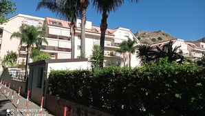 Un quartier résidentiel avec des immeubles à plusieurs étages, des palmiers et un paysage vallonné en arrière-plan.