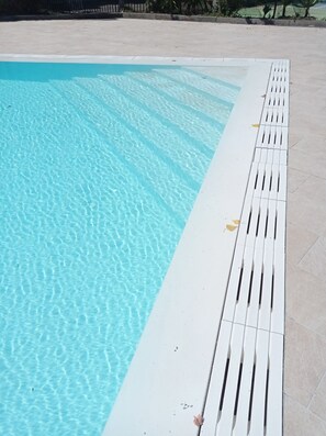 A swimming pool with clear water and a white poolside area.
