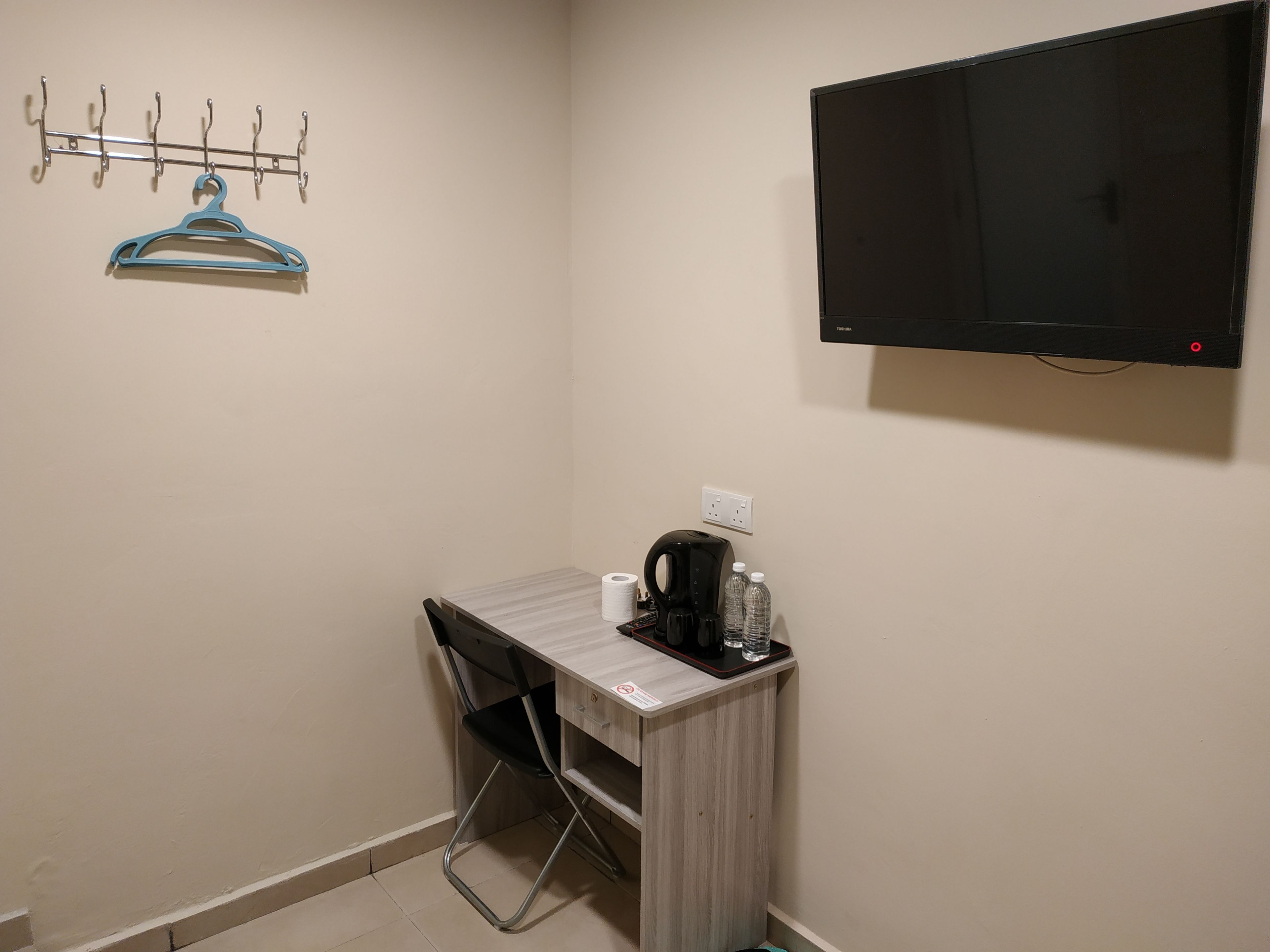 A small room with a desk, chair, and a mounted TV.