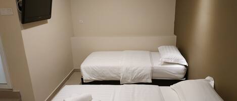 A hotel room with two beds, a flat-screen TV, and an air conditioning unit.