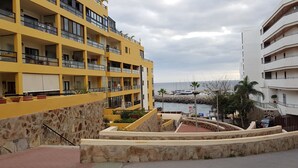 A multi-story hotel with balconies, a stone wall, and a view of the sea. - APARTMENT WITH PRIVATE SOLARIUM ON THE LAST FLOOR, WiFi, HEATED POOLS, (TENERIFE)