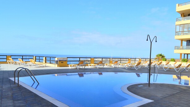 A pool area with lounge chairs and a view of the sea. - APARTMENT WITH PRIVATE SOLARIUM ON THE LAST FLOOR, WiFi, HEATED POOLS, (TENERIFE)