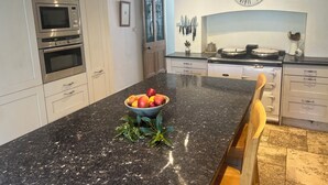 Une cuisine moderne dotée d’appareils électroménagers en acier inoxydable, d’un plan de travail en granit et d’une horloge murale.