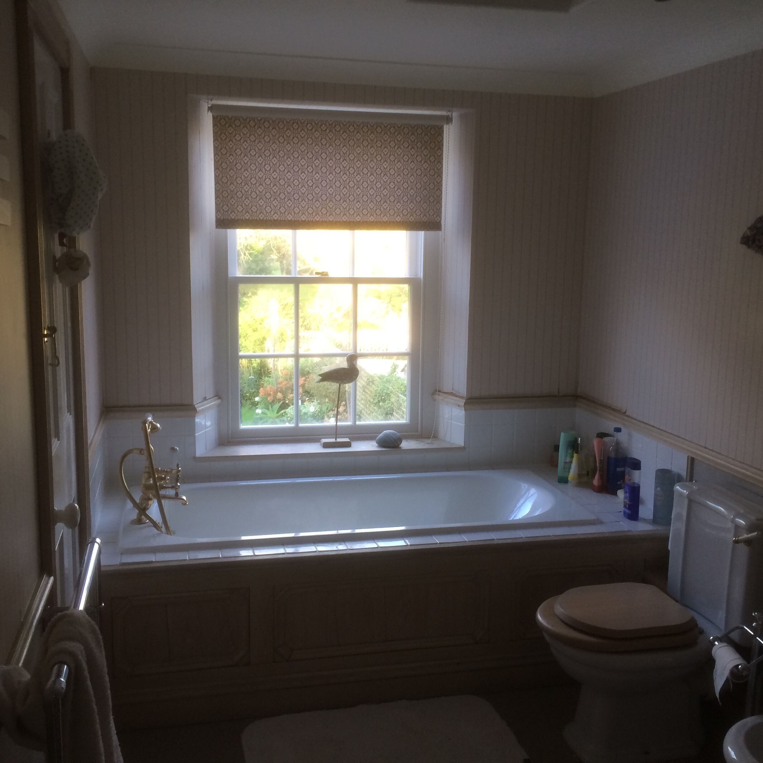 A bathroom with a bathtub, toilet, and window.