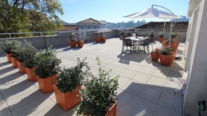 A rooftop terrace with potted plants, a table with chairs, and a large umbrella. - OPO-APT 112-R Terrace apartment in city center. Soberb view on a huge terrace. (Porto)
