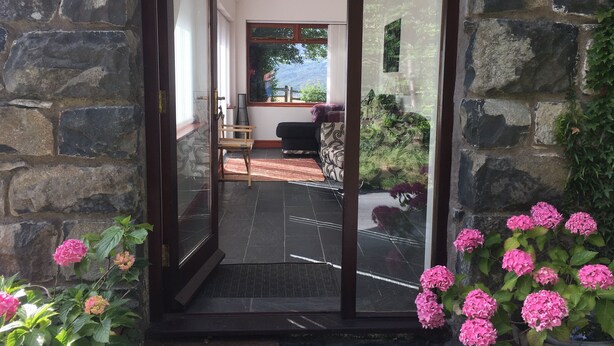 A stone exterior wall with a glass door leading to a patio area.