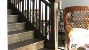 Una escalera de madera con barandilla oscura y un cerramiento de cristal en la parte superior.