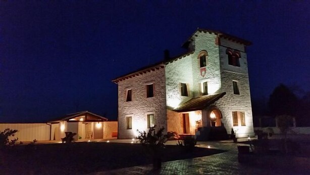 Un edificio de piedra con una torre, iluminado por luces exteriores.