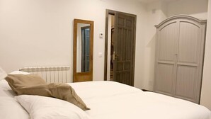 Un dormitorio con cama, armario y espejo.
