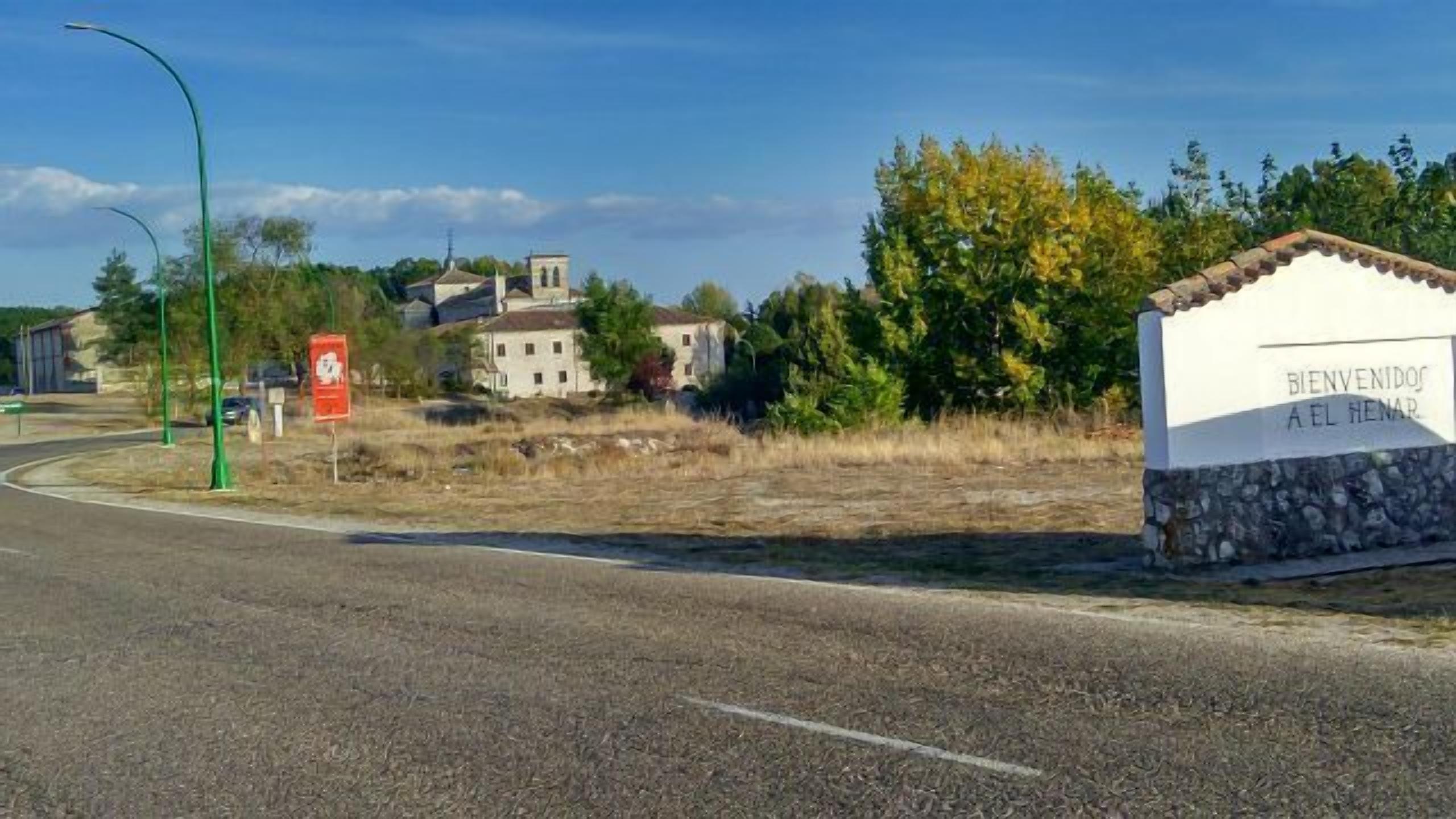 A rural road with a sign welcoming visitors to El Hena.