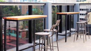Terraza en la azotea con mesas y sillas, que ofrece vistas a un paisaje urbano.