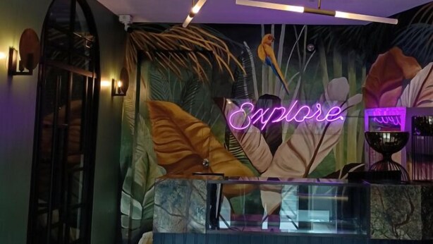 Zona de recepción con un letrero de neón que dice "Explore".