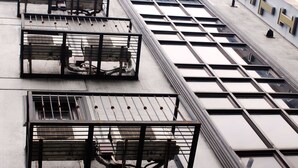 Un edificio con varios balcones, cada uno con barandillas de metal y vistas al cielo.
