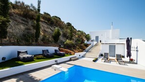 A modern pool area with a clear blue pool, outdoor seating, and a staircase leading to a white building. - Paros Nereids Villas Estate with private pools and amazing  view (Paros)