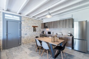 A modern kitchen with a stone wall, wooden cabinets, and a stainless steel refrigerator.