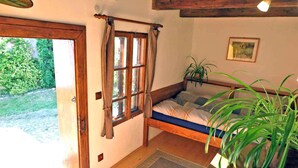 Un dormitorio acogedor con una cama de madera, una ventana con cortinas, una planta en maceta y un cuadro en la pared.