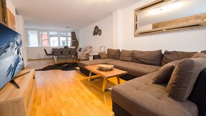 Een moderne woonkamer met een ruime hoekbank, een houten salontafel en een eethoek met stoelen en een tafel.