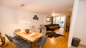Een eetgedeelte met een houten tafel en stoelen, een bank en een lederen vloerkleed.