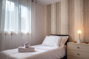 A neatly made bed with white linens and a folded towel, a bedside table with a lamp, and a window with sheer curtains. - Holiday Home in Lukoran with Seaview, Terrace, Air condition, WIFI (4200-1) (Lukoran)