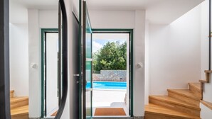 Un interior moderno con una puerta de cristal que da a una zona de piscina al aire libre.
