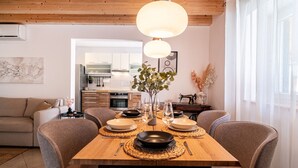 Un comedor con una mesa de madera dispuesta para cuatro personas, rodeada de sillas. Una lámpara colgante grande ilumina la mesa.