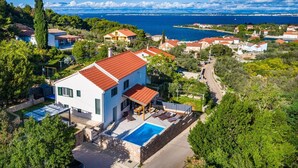 Una villa moderna con piscina, rodeada de exuberante vegetación y vistas al mar.