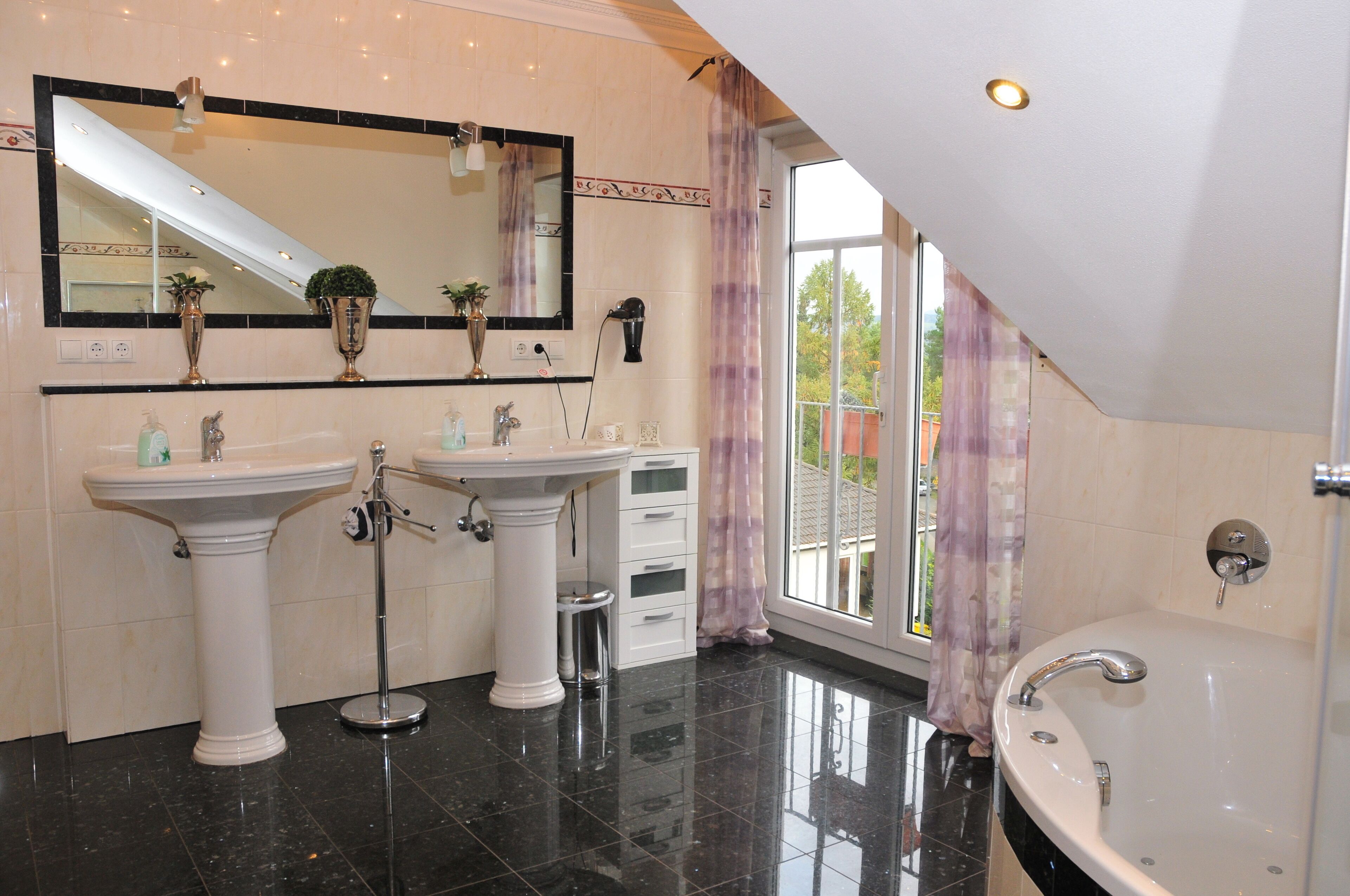 A bathroom with two sinks, a large mirror, and a bathtub.